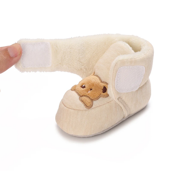 Open hook-and-loop strap on a beige bear baby boot, showing the plush interior