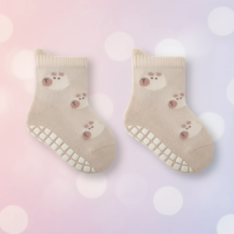 Pair of beige bear-pattern baby socks with white grip dots on the soles.
