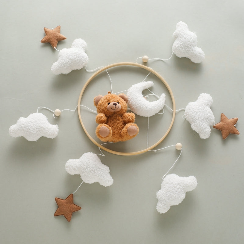 Brown bear mobile laid flat with its circular frame, white clouds, stars and crescent moon