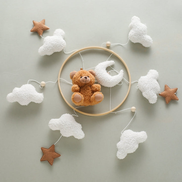 Brown bear mobile laid flat with its circular frame, white clouds, stars and crescent moon