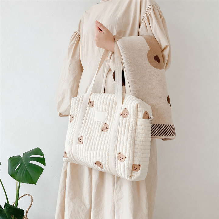 Person carrying a bear-print quilted diaper bag over one shoulder