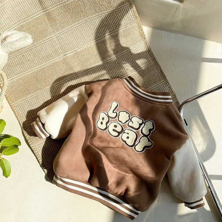 Back of the brown baseball jacket with bear-themed lettering and a striped hem
