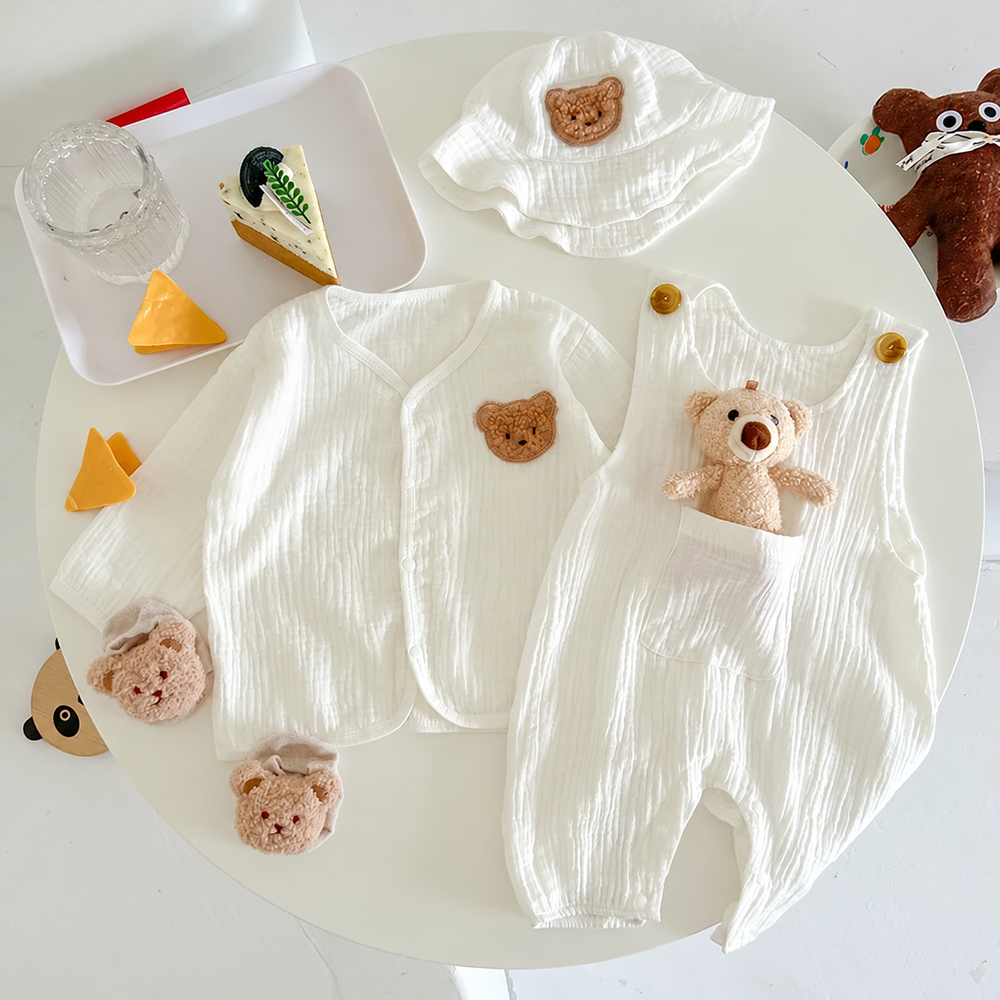 Off-white bear-motif top, overalls and matching hat arranged on a round table