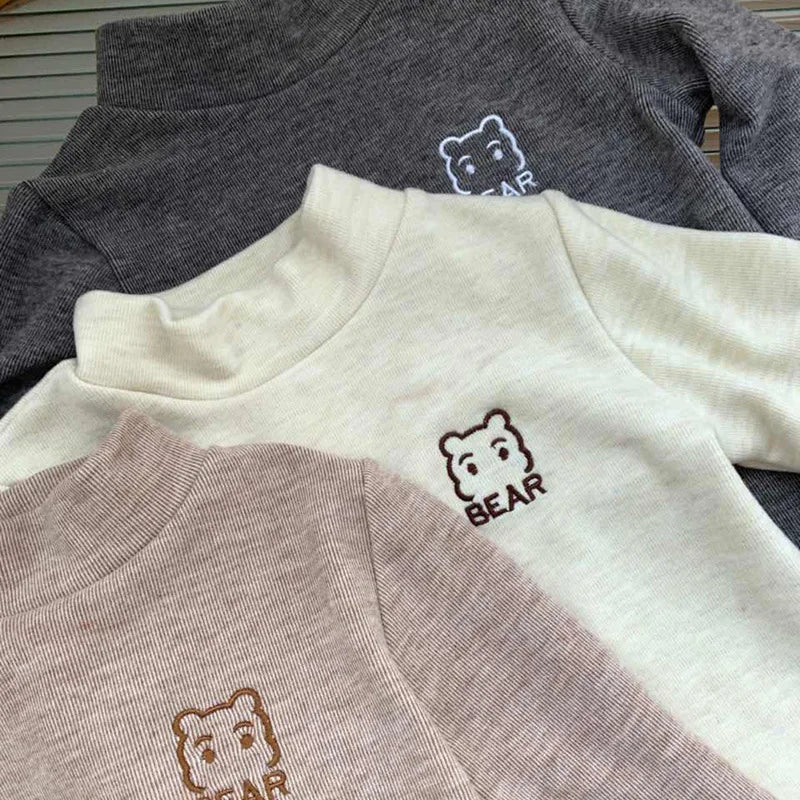 Close-up of the high necklines and bear chest motifs on three fleece shirts