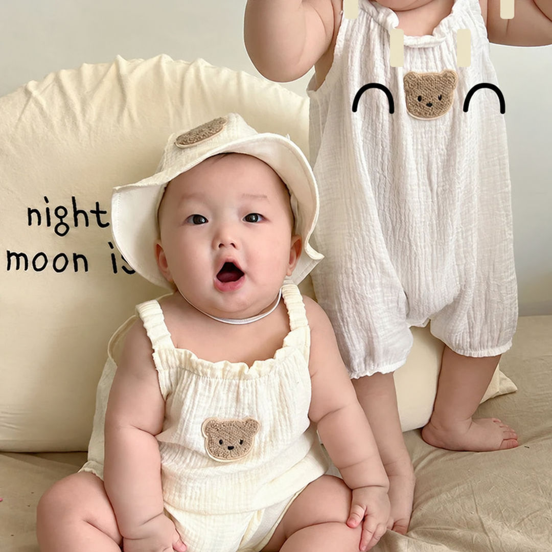 Seated and standing babies wearing textured bear-patch overalls, with a hat on the seated baby