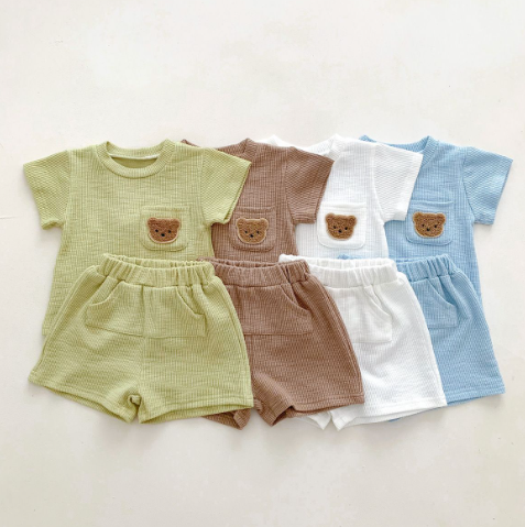 Green, brown, white, and blue T-shirts with coordinating shorts laid side by side
