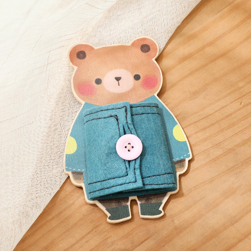 Bear dressing board with a teal fabric coat and pink button on a wooden floor