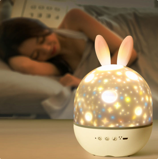 Bunny-ear star projector on a bedside table in a softly lit bedroom