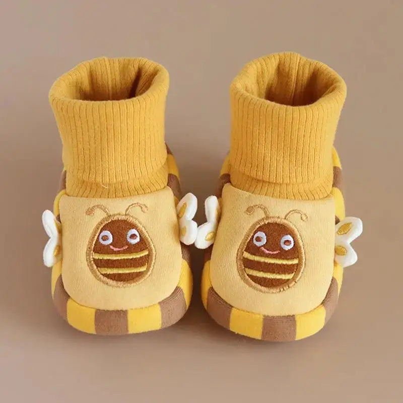 Pair of yellow bee indoor shoes with tall ribbed cuffs on a beige surface