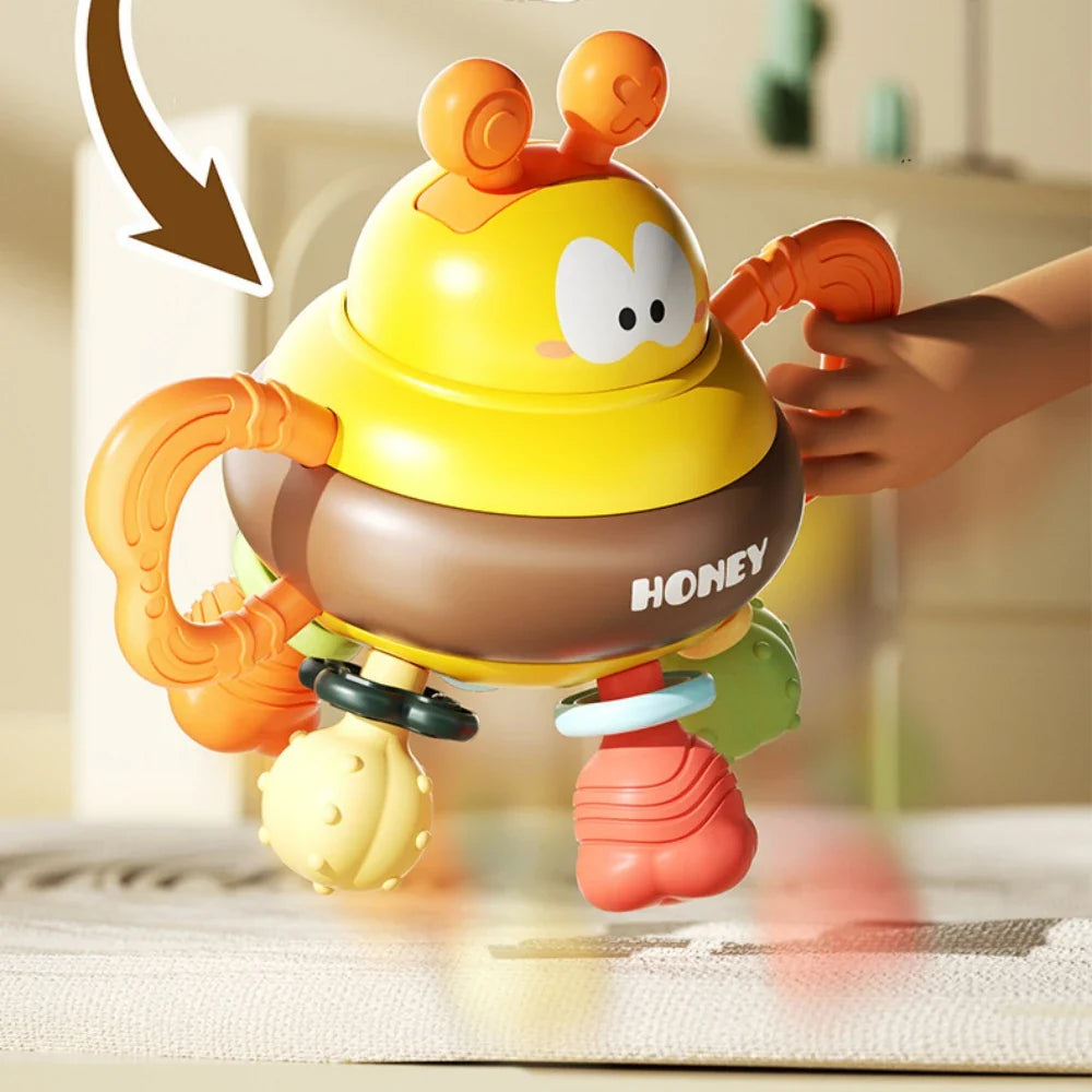 Bee rattle held by one orange handle, showing its rounded body and hanging textured pieces