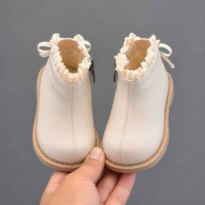 Front view of beige ankle boots with rounded toes and decorative ankle trim