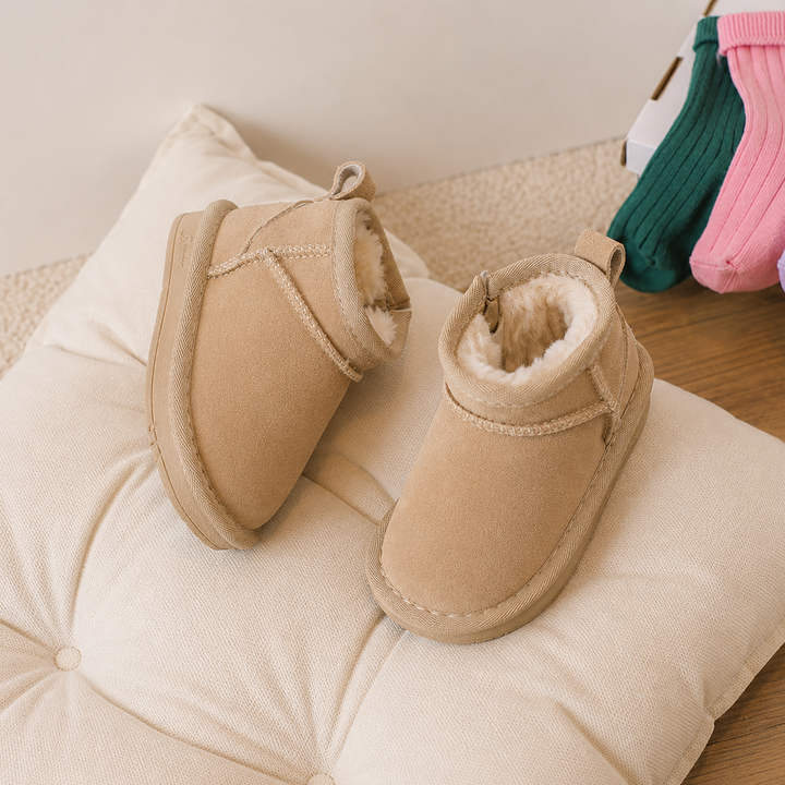 Beige suede-look ankle boots arranged on a cream tufted cushion