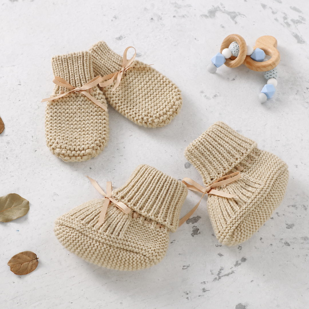 Beige knitted baby booties and matching mittens with ribbon bows
