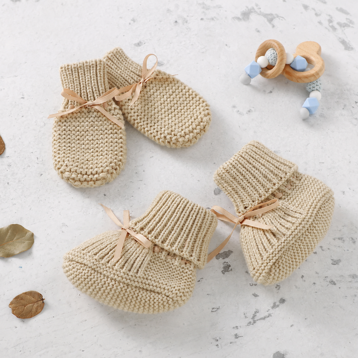 Beige knitted baby booties and matching mittens with ribbon bows