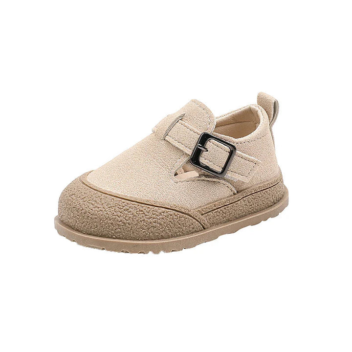 Side view of a beige baby shoe with a buckle detail and textured sole edge