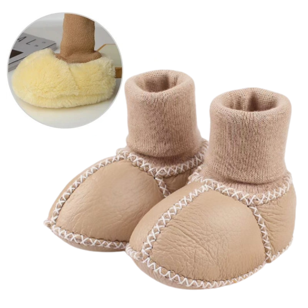 Beige baby slippers with rolled knit cuffs and stitched panel seams