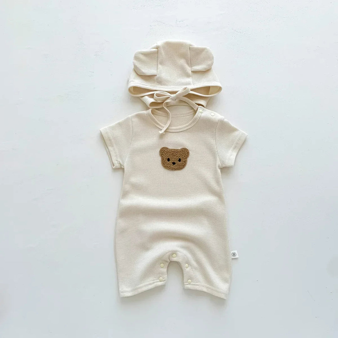 Beige bear-detail baby romper with leg snaps and a matching tie hat
