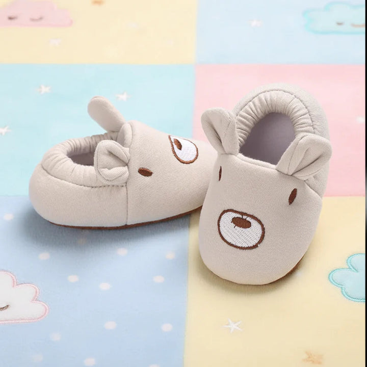 Beige bear-face baby shoes with rounded ears and gathered ankle cuffs.