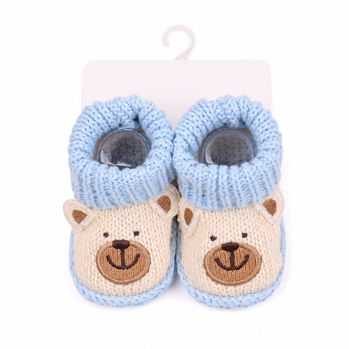 Beige bear knitted booties with blue cuffs displayed on a hanging card