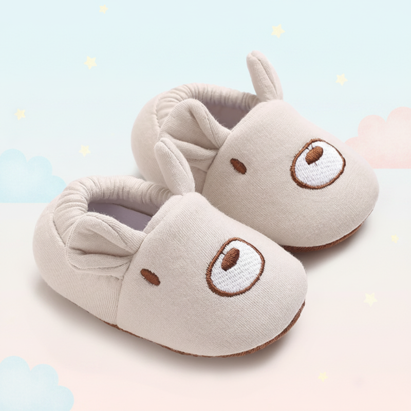 Beige bear-face crib shoes showing rounded ears and gathered ankle openings.