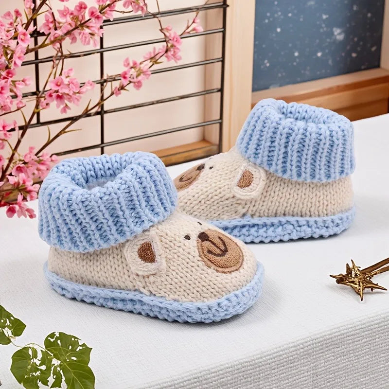 Beige bear baby booties with light blue ribbed cuffs, shown from the front and side