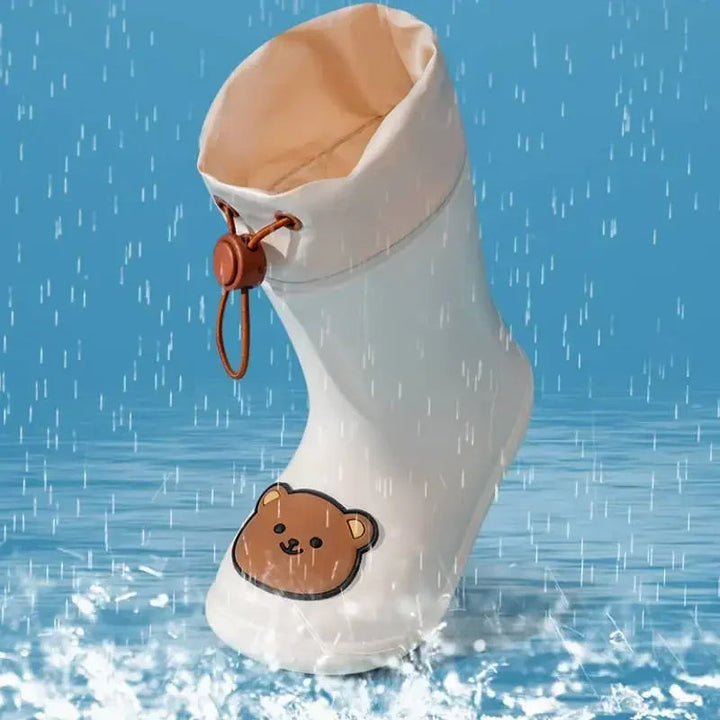 Beige bear rain boot shown splashing in a rain-and-puddle display