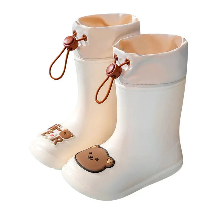 Pair of beige bear rain boots with brown drawstrings and cartoon toe decorations