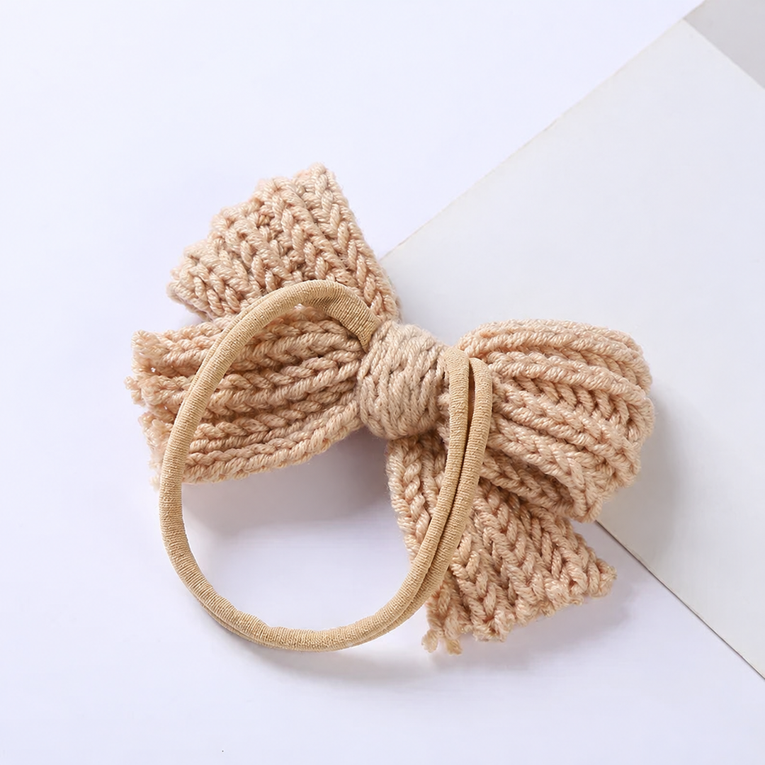 Back of a beige knitted bow headband showing the stretch band attachment