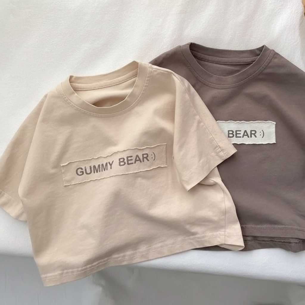Beige and brown Gummy Bear T-shirts displayed together on white bedding
