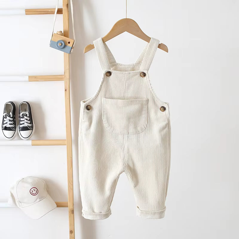 Beige corduroy overalls hanging with buttoned straps, a front pocket, and rolled cuffs