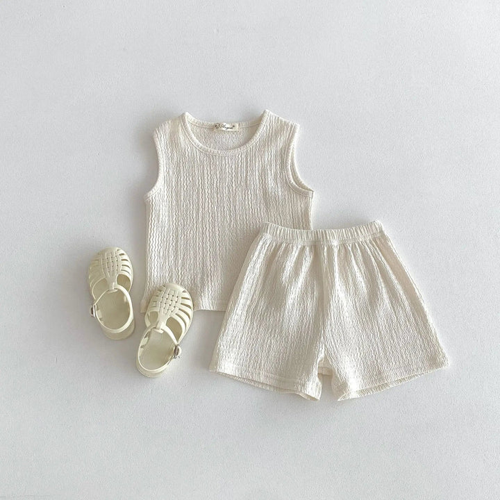 Beige sleeveless cotton top and matching shorts with sandals alongside.