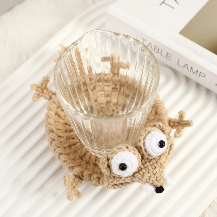 Clear glass resting in the round center of a beige crocheted animal coaster