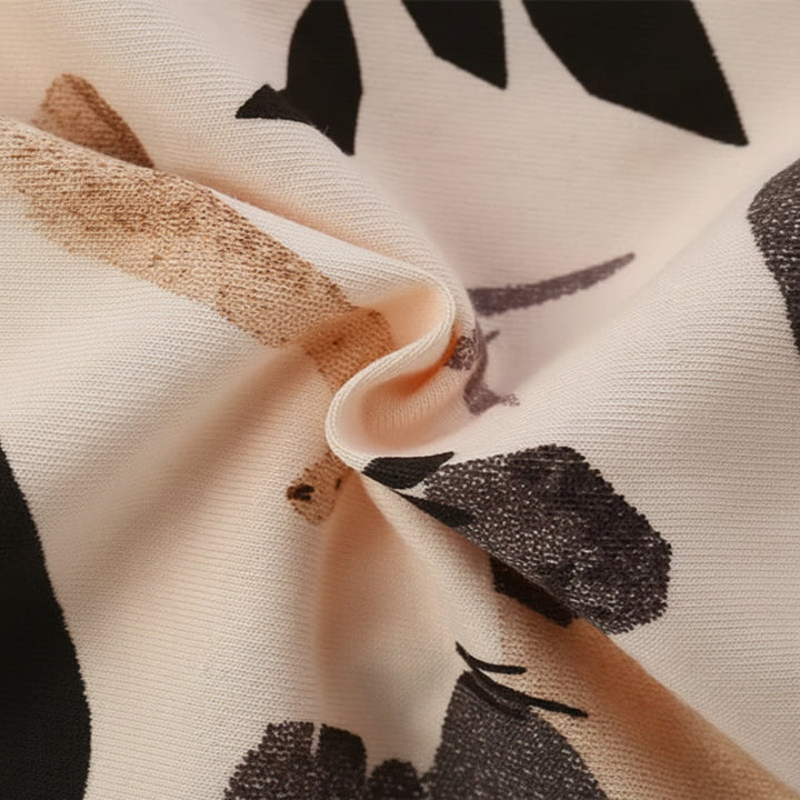 Close-up of folded beige cotton fabric with a dark dinosaur print