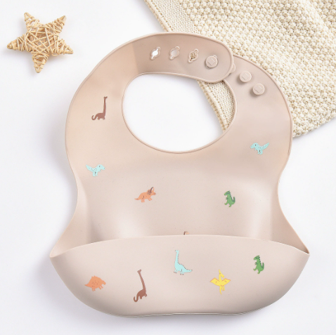 Beige silicone baby bib with multicolored dinosaurs and a wide food-catching pocket