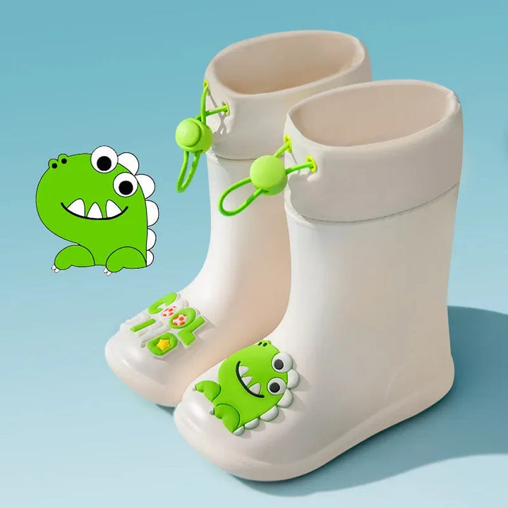 Beige dinosaur rain boots with green drawstrings and cartoon toe details