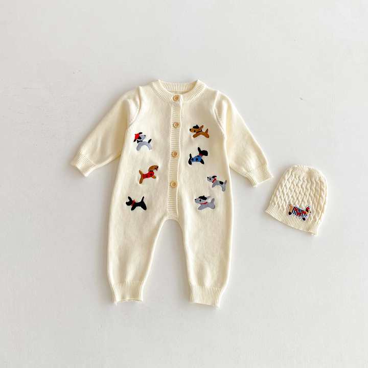 Beige dog-pattern knitted baby jumpsuit laid flat beside a beige knit hat