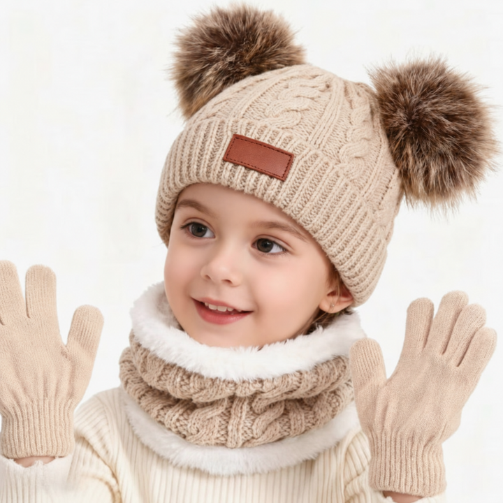 Child wearing a beige double-pom-pom knit hat, matching loop scarf, and gloves