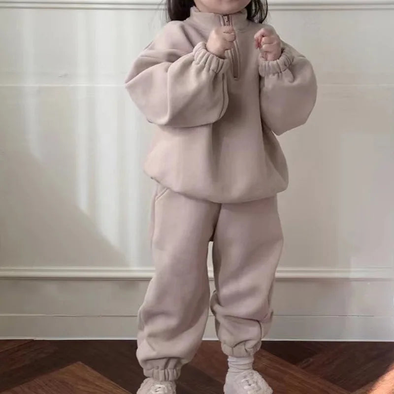 Child wearing a beige fleece tracksuit with a zip-neck top and matching pants