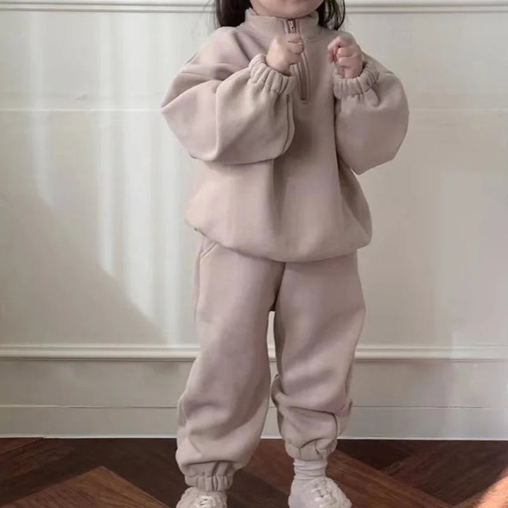 Child wearing a beige fleece tracksuit with a zip-neck top and matching pants