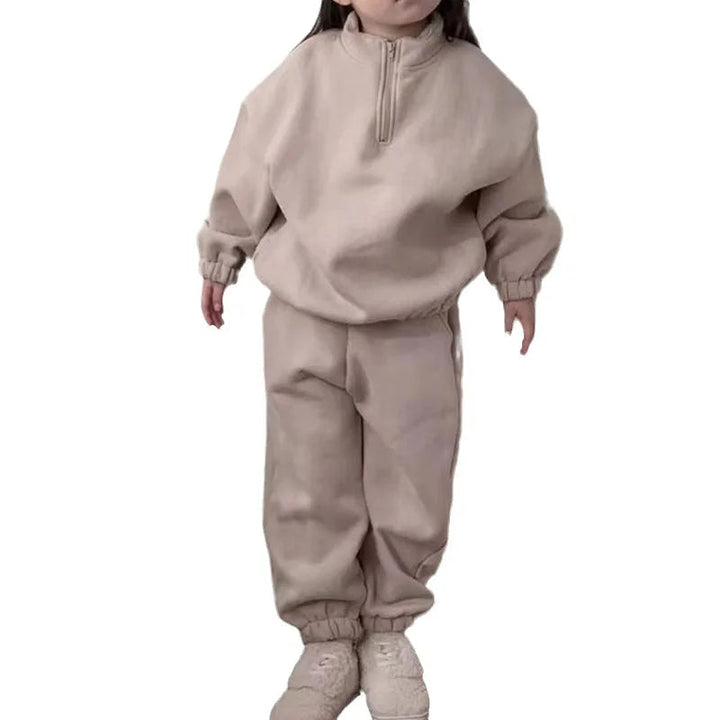 Child modeling a beige fleece tracksuit with a relaxed fit and gathered cuffs