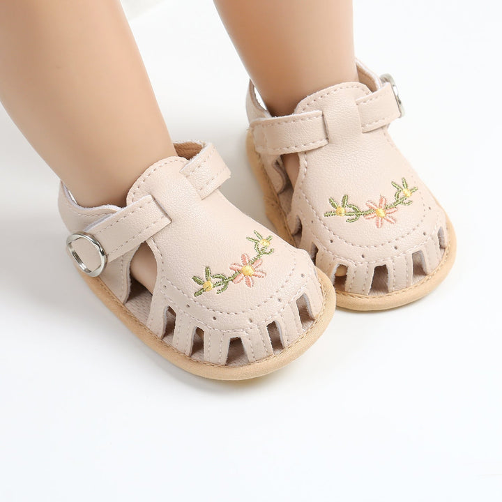 Beige floral baby sandals with rounded cutout toes on mannequin feet