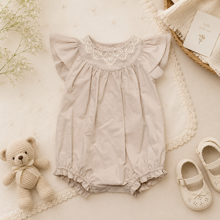 Beige baby romper with flutter sleeves, a gathered bodice, and a decorative lace neckline.