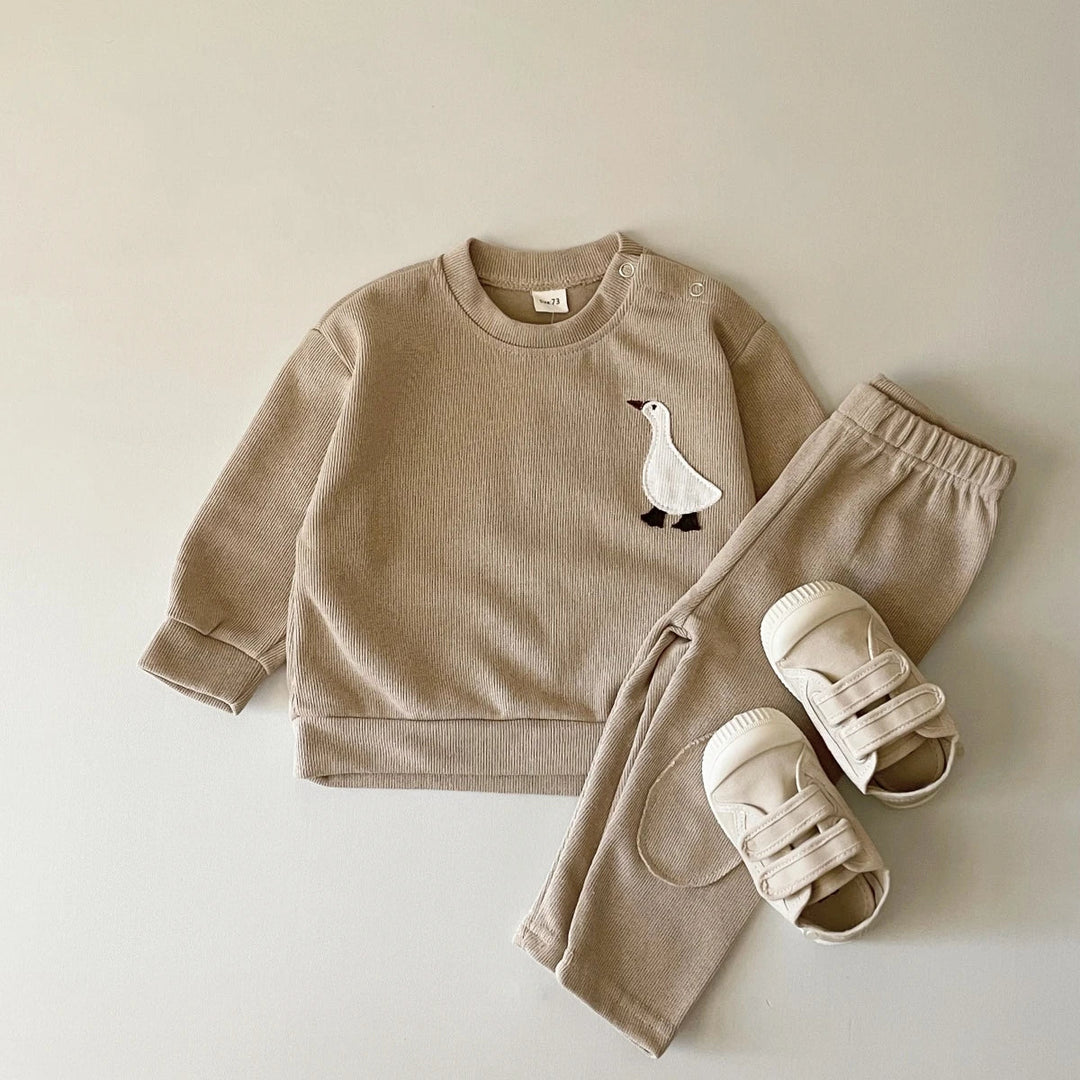 Beige goose tracksuit with a round-neck sweater and matching pants, styled with sandals