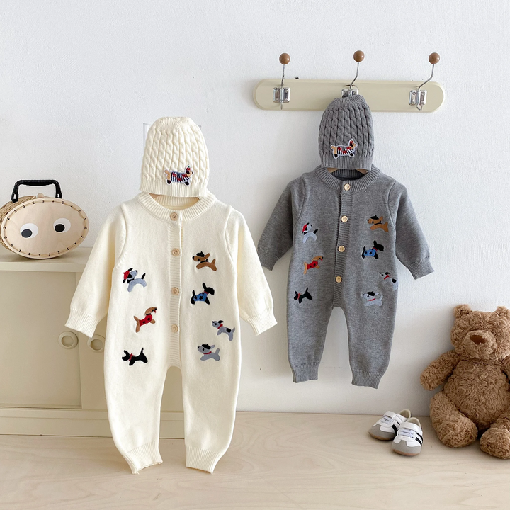 Front view of beige and gray dog-pattern baby jumpsuits hanging beneath knitted hats