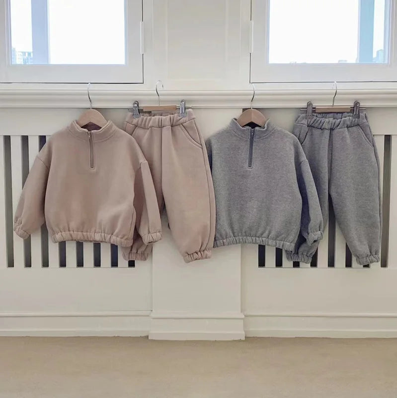Beige and gray fleece tracksuits with matching tops and pants displayed side by side