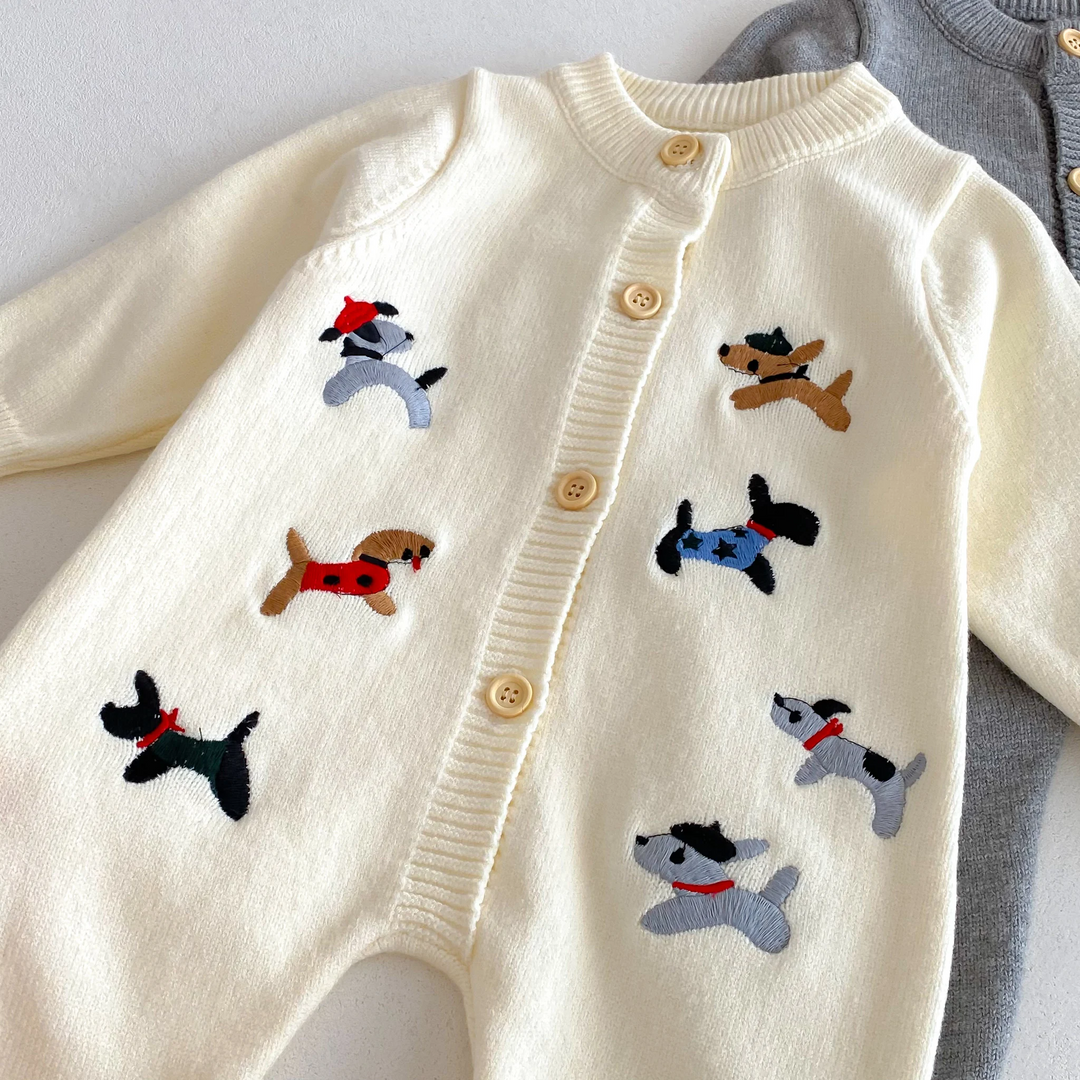 Beige knit baby jumpsuit with colorful dog motifs and a front button closure