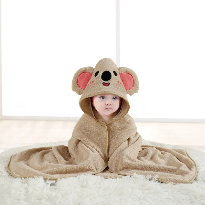 Child wrapped in a beige koala hooded bath towel with pink inner ears