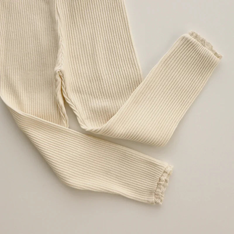 Beige cotton leggings showing fine ribbing and lace detail at the ankle openings.