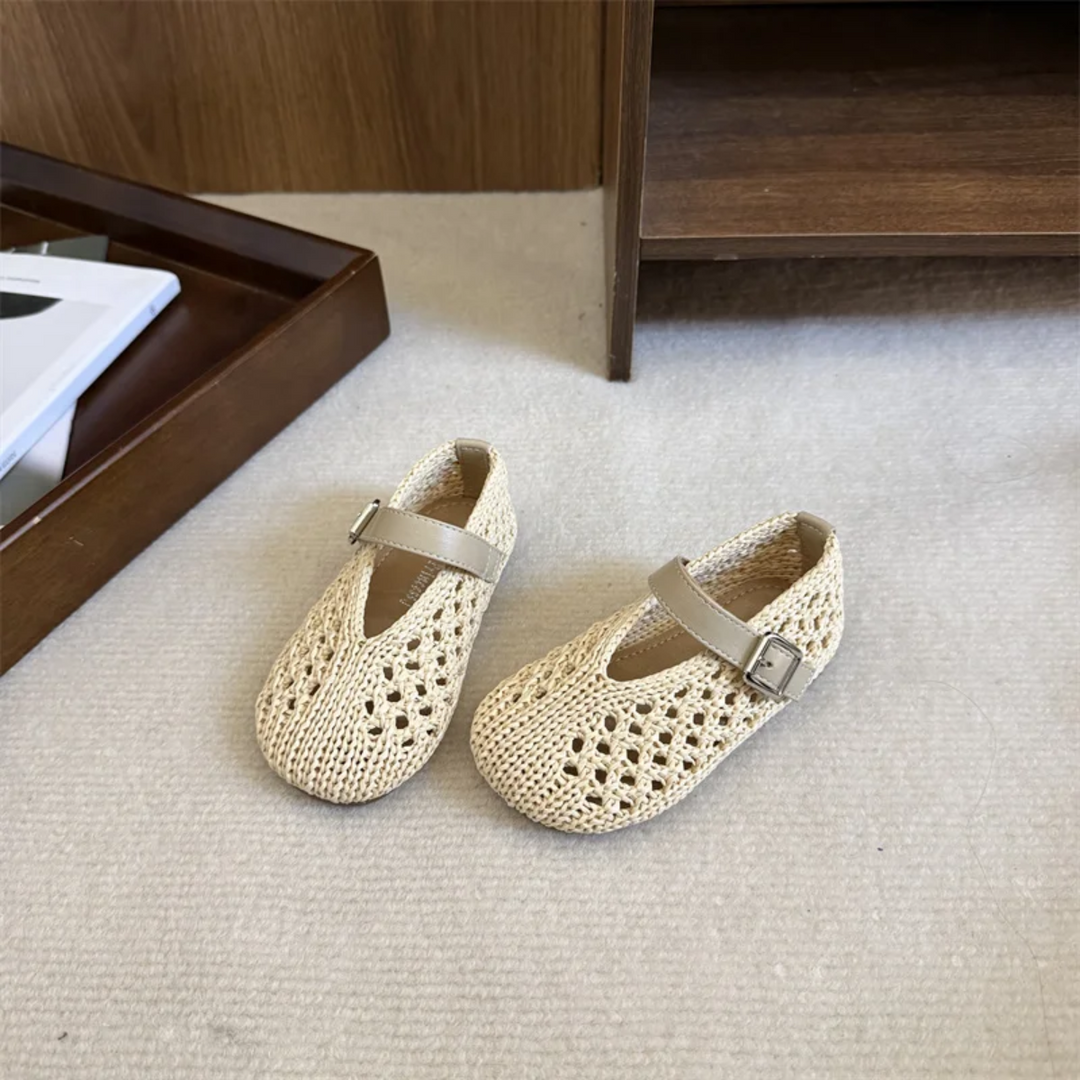 Pair of beige Mary Jane flats on carpet in front of an open wooden cabinet