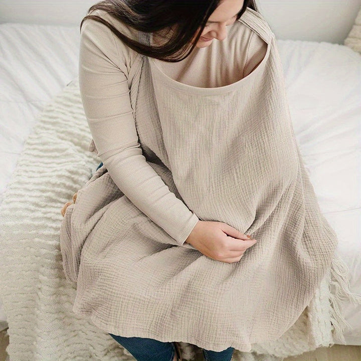 Seated mother wearing a beige nursing cover with a wide neckline